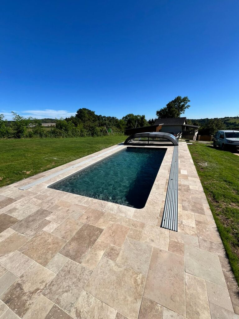 Piscine avec abri, liner gris anthracite, terrasse en travertin naturel, engazonnement